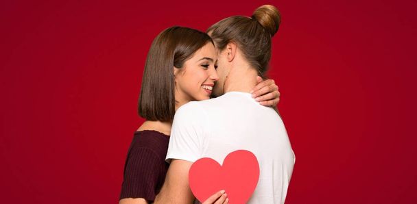 Couple in valentine day hugging and with a rose over red background - Foto, imagen