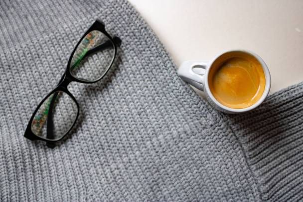 Κούπα Espresso κοντά το γκρι πουλόβερ με τα γυαλιά - Φωτογραφία, εικόνα