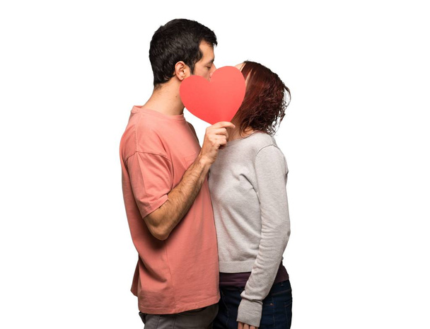 Paar am Valentinstag hält ein Herzsymbol in der Hand und küsst sich auf isoliertem weißem Hintergrund - Foto, Bild