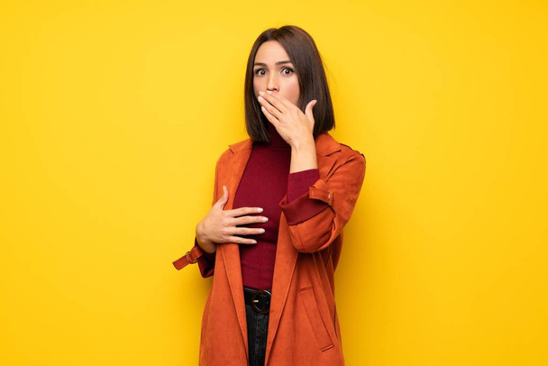 Young woman with coat nervous and scared putting hands to mouth - 写真・画像