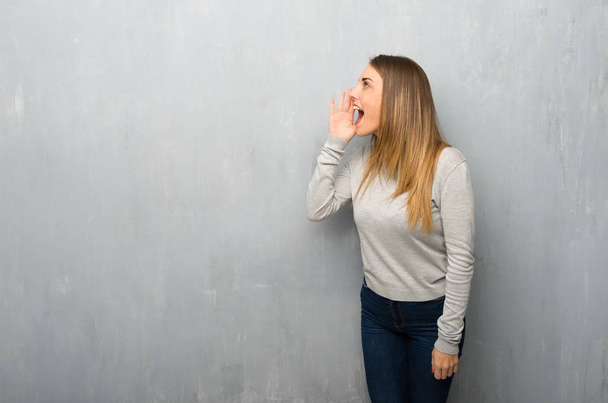 Jeune femme sur mur texturé criant avec la bouche grande ouverte sur le côté
 - Photo, image