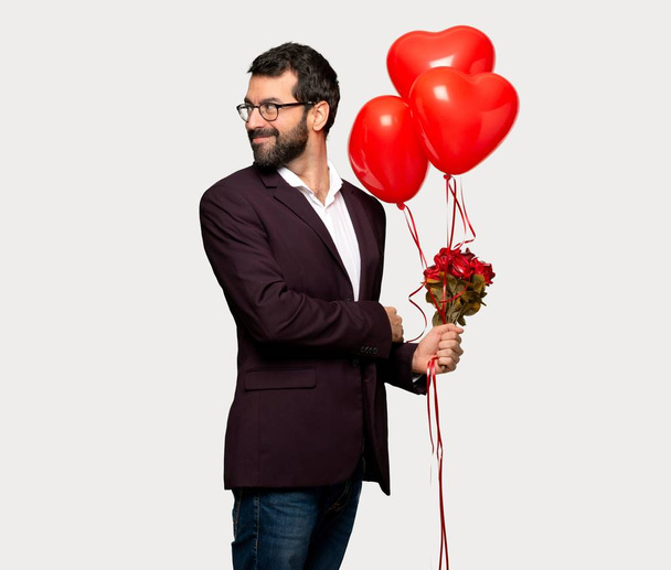 Man in valentine day looking over the shoulder with a smile over isolated grey background - Foto, Imagen