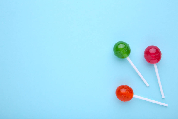 Red and green sweet lollipops on blue background - Fotoğraf, Görsel