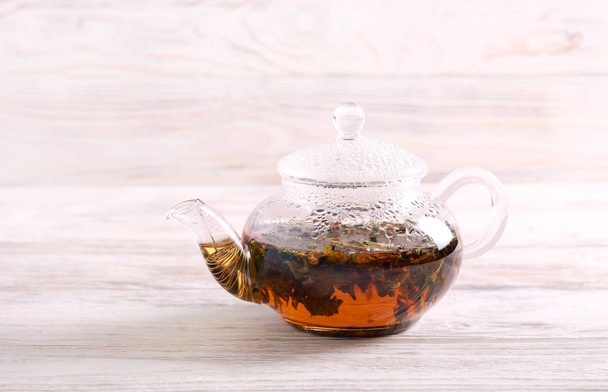 Hot herbal tea in a kettle over wooden background - Foto, Imagem