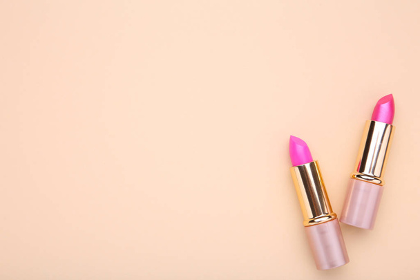 Two pink lipsticks on beige background. Cosmetic - Fotó, kép
