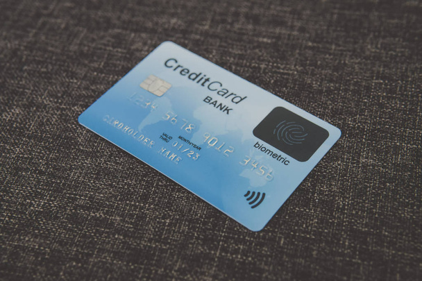 Close up of credit biometric card belonging to abstract cardholder lying on coarse fabric. E-shopping using advantages of fingerprint scanning. Simplicity and security of biometrics in banking. Chip. - Photo, Image