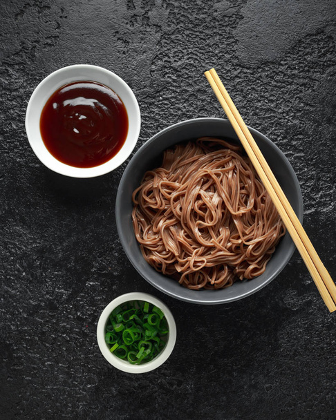 Χυλοπίτες, φαγόπυρο σε ένα μαύρο μπολ, με φρέσκο κρεμμυδάκι και σουσάμι. Παραδοσιακή ιαπωνική τροφίμων. - Φωτογραφία, εικόνα