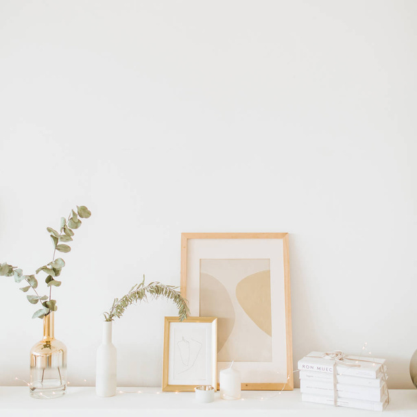 Styled interior design composition. Photo frame, eucalyptus branch, vase on white table. Trendy Scandinavian living room. - Zdjęcie, obraz