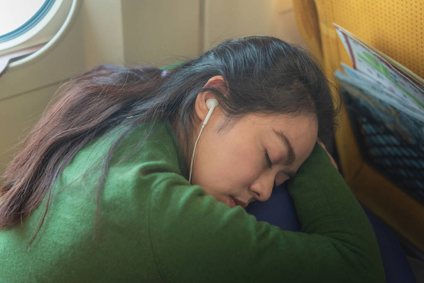 美しいアジアの女性は、残りの部分し、電車の中で眠っている旅行の自己を準備します。. - 写真・画像