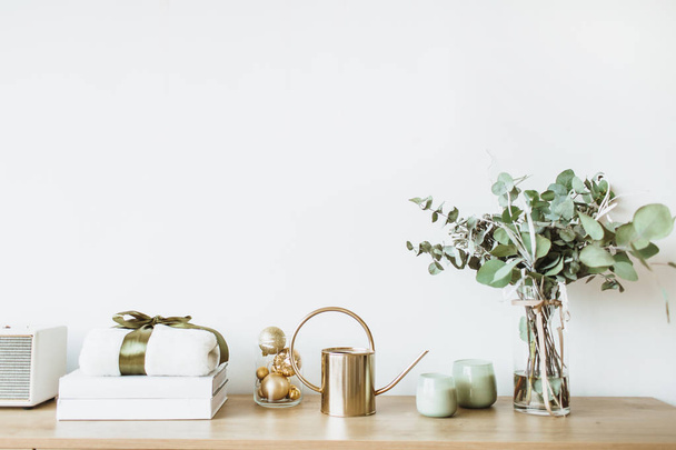 Moderne interieur concept. Minimale Nordic Scandinavische stijl woonkamer met houten tafel met de doos van de gift, bloemen boeket met eucalyptus, kaarsen, radio op de witte muur. Pastel appartement te huur. - Foto, afbeelding