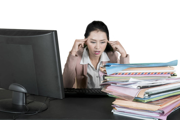 Image of overworked businesswoman having a headache while looking at a pile of documents in the studio - Photo, Image