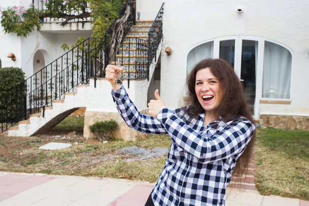 Nouvelle maison, maison, propriété et locataire - Jeune femme drôle tenant la clé devant sa nouvelle maison après avoir acheté de l'immobilier
 - Photo, image