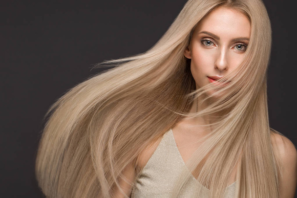 Beautiful blond girl in move with a perfectly smooth hair, and classic make-up. Beauty face. - Фото, зображення