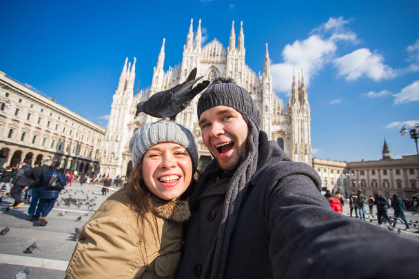 Ταξίδια, Ιταλία και αστεία ζευγάρι έννοια - χαρούμενων τουριστών λήψη αυτοπροσωπογραφία με περιστέρια μπροστά στον καθεδρικό ναό Duomo, Μιλάνο - Φωτογραφία, εικόνα