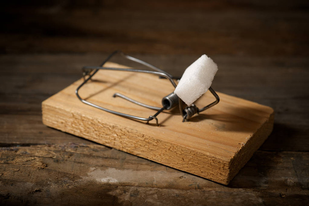 Cube de sucre dans un piège à souris sur une table en bois
. - Photo, image