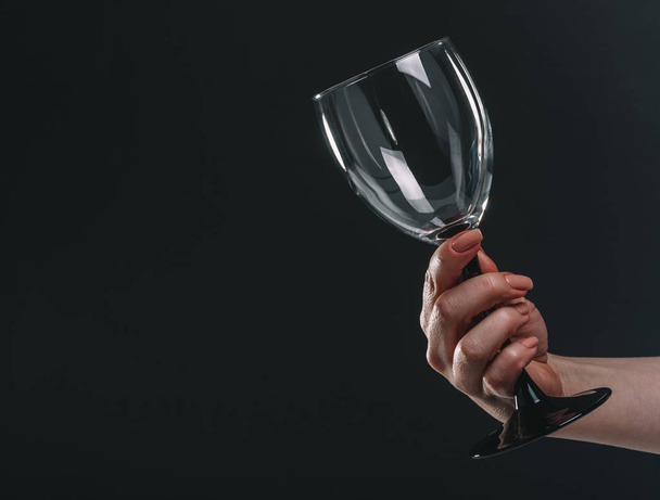 empty wine glass in female hand on black background - Zdjęcie, obraz