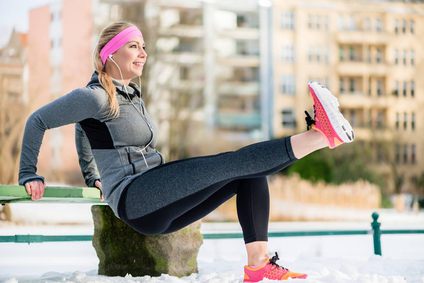 Mujer estirando sus extremidades para hacer ejercicio deportivo en invierno
 - Foto, Imagen
