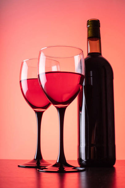 wine glasses and bottle on red background - Fotoğraf, Görsel