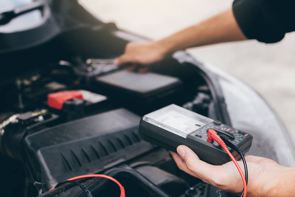 The car mechanic is carrying a battery meter and checking the general condition of the engine. - Foto, Bild