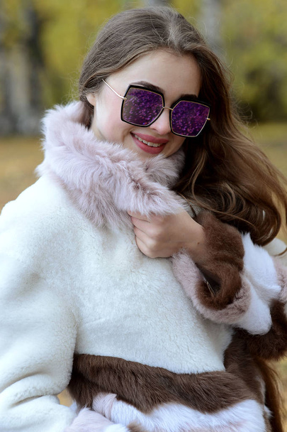 girl in a coat and sunglasses walking in the woods - Фото, зображення