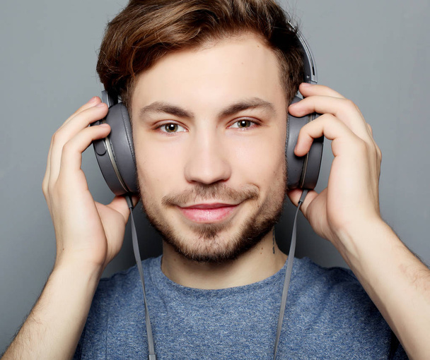  Happy young stylish man  adjusting his headphones ad smiling wh - Foto, afbeelding
