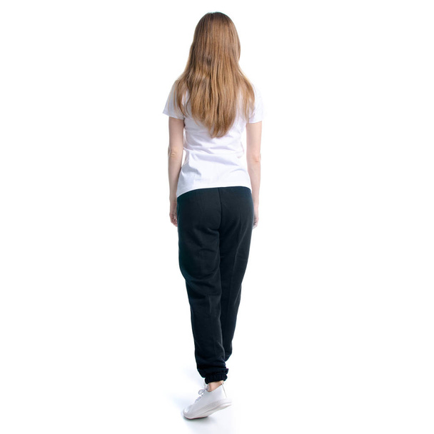Woman in black sweatpants and white t-shirt walking goes - Fotó, kép