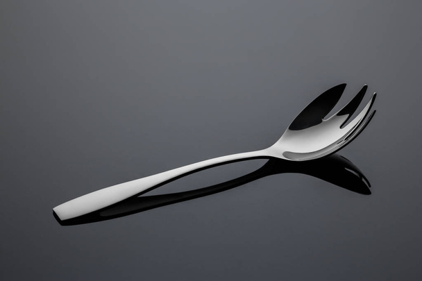 Stainless steel salad fork on a gray reflective surface - Photo, Image