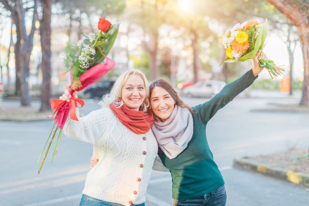 Blond hair excited middle aged lady looking surprised at the flower bouquet given by her man who sits in a car - spring, date and women's day celebration concept - Foto, Bild