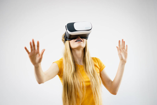 Young woman wearing virtual reality goggles headset, vr box, stretching arms. Connection, technology, new generation and progress concept. Studio shot on gray - Photo, image