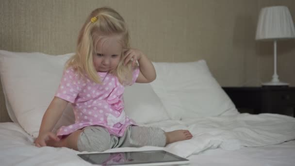 Little baby girl with tablet on bed. - Filmagem, Vídeo