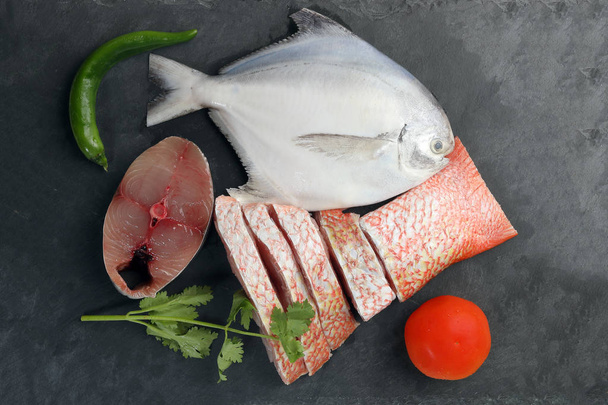 Белая помфрет Испанская скумбрия красная снэппер рыба очищена от обескровленных нарезанных кусочков филе на черном мраморном фоне
 - Фото, изображение