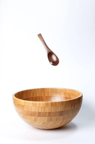 Dřevěná miska lžíce nádobí na bílém pozadí zvýšená, létání, plovoucí  - Fotografie, Obrázek