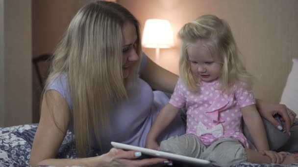 A woman and a child with a tablet on the bed in the room. - Footage, Video