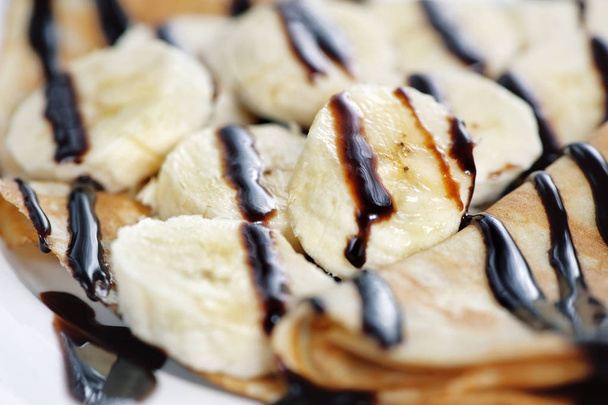 Thin delicious pancake with banana and chocolate on white backgroun - Φωτογραφία, εικόνα