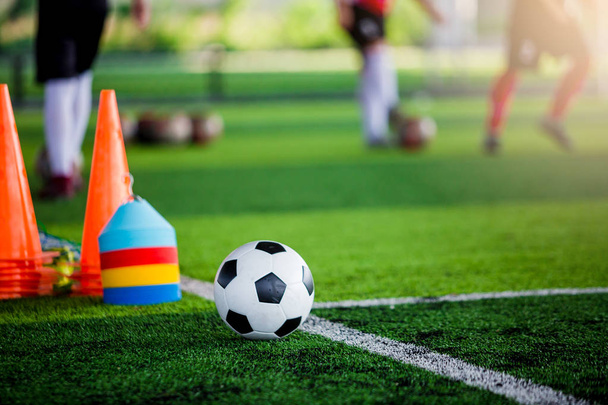 Piłka nożna i piłka nożna sprzęt treningowy zielonej trawy syntetycznej z niewyraźne graczy piłka nożna szkolenie. Akademia piłkarska. - Zdjęcie, obraz