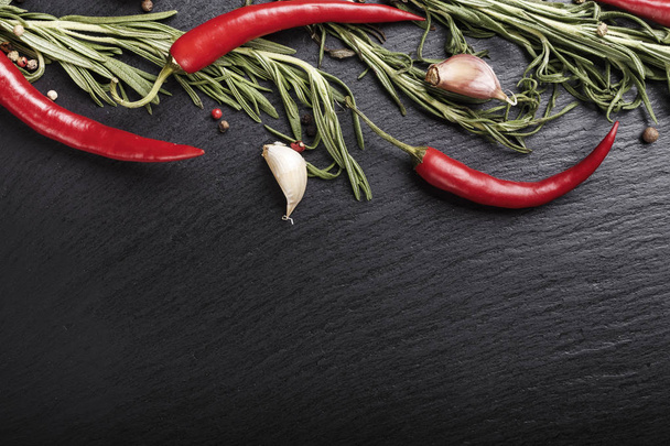 red pepper with rosemary and garlic on a black slate background. space for tex - Foto, imagen