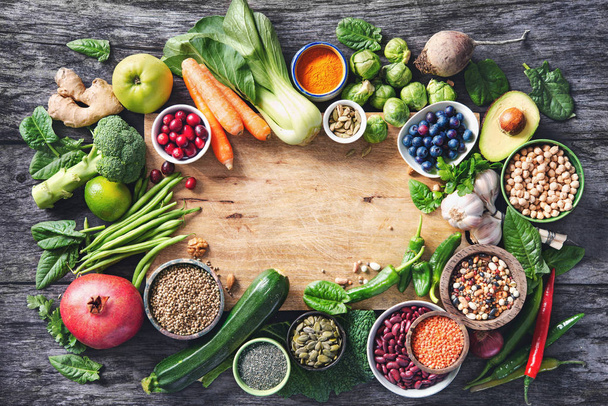 Terveellinen ruokavalikoima hedelmiä, vihanneksia, siemeniä, superelintarvikkeita, viljaa harmaalla puupohjalla
 - Valokuva, kuva
