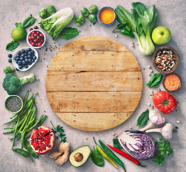 healthy food selection with fruits, vegetables, seeds, super foods, cereals and the wooden board in the middle as copy space - Photo, image