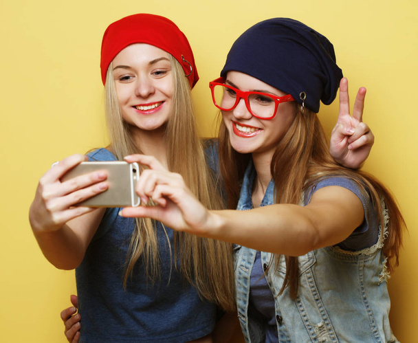 two young hipster girls friends  taking selfie over yellow background - Foto, immagini
