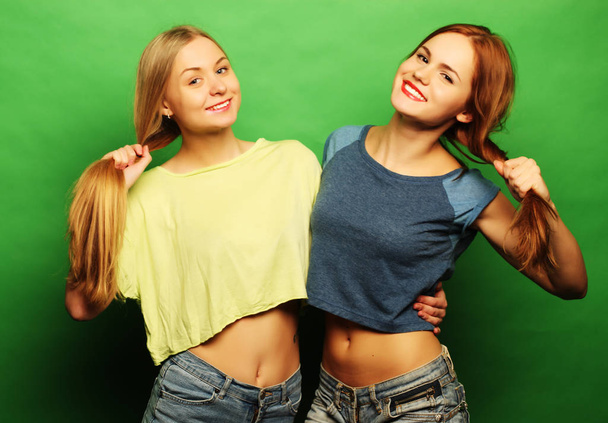 two  hipster girls best friends over green background - Photo, image
