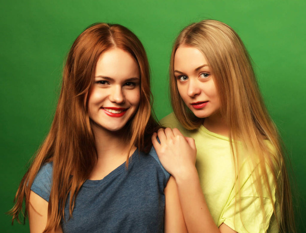 two  hipster girls best friends over green background - 写真・画像