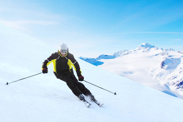 Alpine skier on piste running downhill in beautiful Alpine landscape. Blue sky on background. Free copy space for text - Φωτογραφία, εικόνα