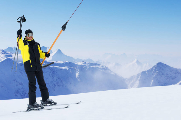 Happy smiling male skier using t bar ski drag lift and greeting waving his ski poles - Φωτογραφία, εικόνα