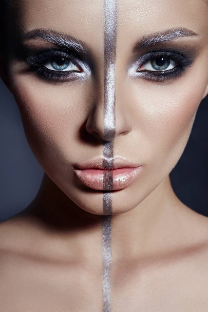 Fashion Perfect makeup, silver color band on the girl face, silver eyebrows and black brunette hair. Creative makeup on woman face, beautiful big eyes. Portrait of a woman on a dark background - Фото, зображення