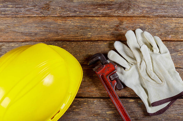 Guantes de trabajo amarillos para sombreros y cuero y llave inglesa construcción de manojo de herramientas manuales y casco
 - Foto, imagen