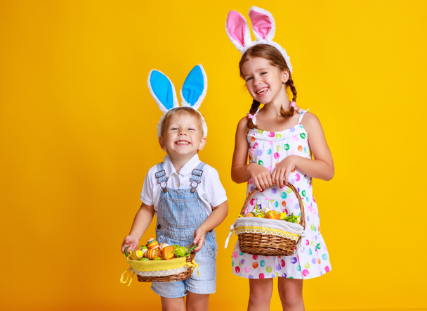 funny happy child boy with easter eggs and bunny ears on yellow background - Photo, Image