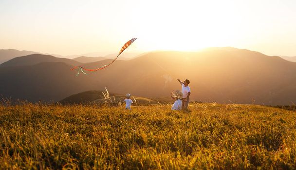 Happy père de famille et les enfants lancent un cerf-volant sur la nature au coucher du soleil
 - Photo, image