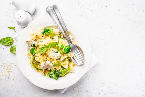 Italian pasta farfalle with broccoli, chicken and cheese in a white plate. White background, top view. - Foto, Imagem
