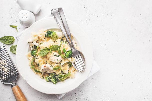 Italian pasta farfalle with broccoli, chicken and cheese in a white plate. White background, top view. - Zdjęcie, obraz