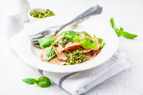 Pumpkin ravioli with pesto sauce in a white plate. Healthy vegan food concept. - Photo, image